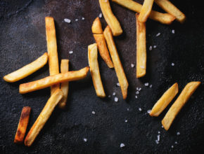 French fries with sea salt over black background
