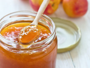 Apricot jam in a glass jar, apricots on wooden background