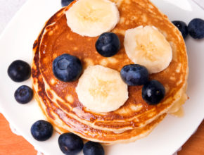 Delicious pancakes with bluebery and bananas on white plate