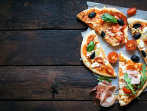 Slices of mini pizza variety served on wooden board and background,from above and blank space