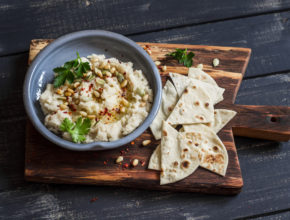 Healthy vegan cauliflower hummus and homemade tortilla on a dark rustic cutting board on a dark background. Delicious healthy snack